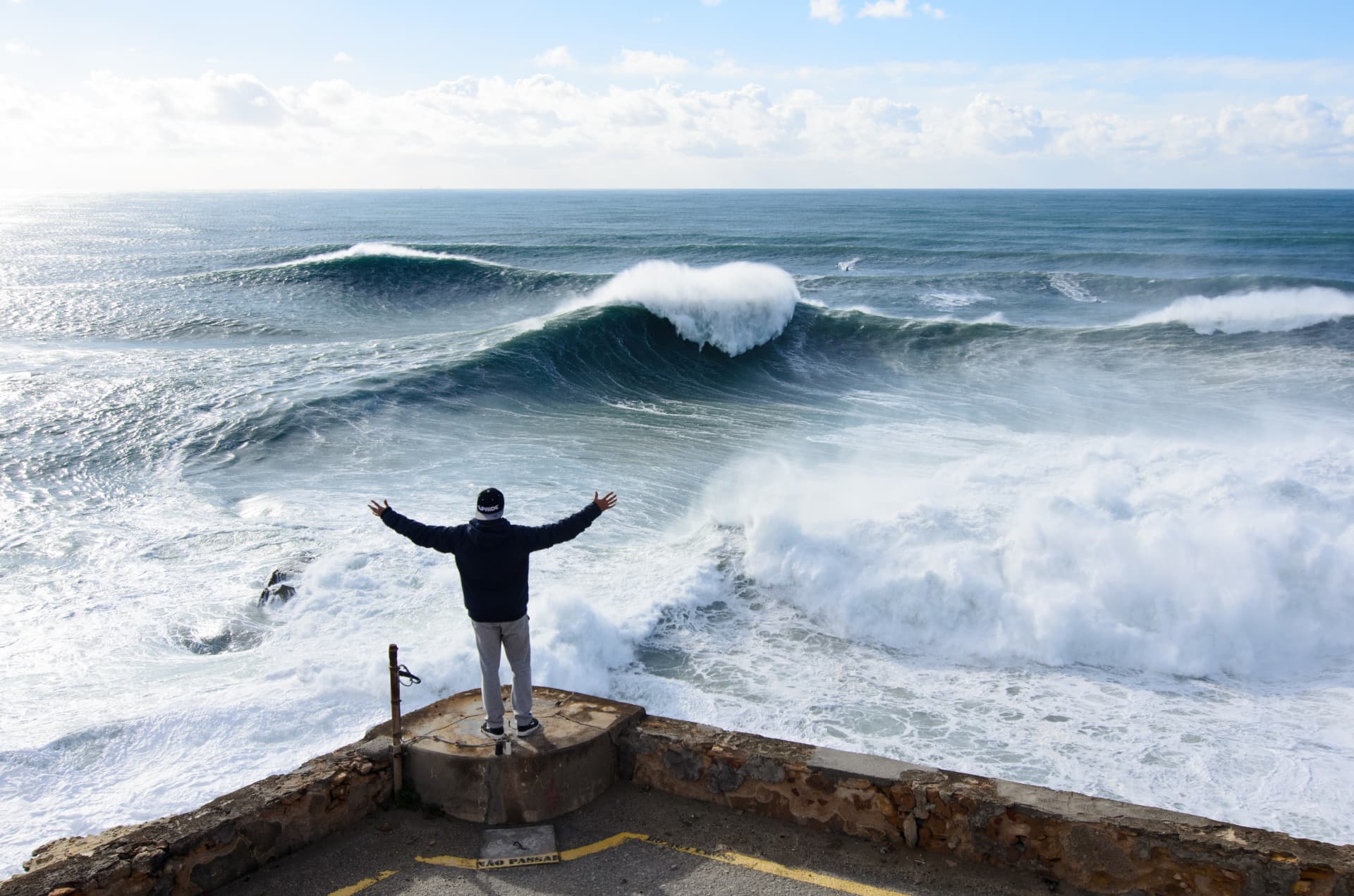 Nic von Rupp standing with his back to the camera in front of the waves at Nazaré